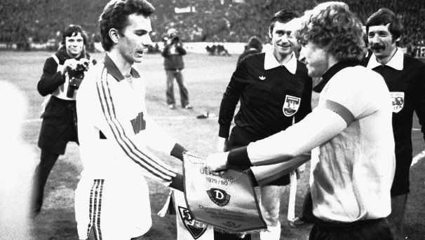 Aufeinandertreffen im Jahr 1979: die beiden Kapitäne Hermann Ohlicher (VfB) und Hans-Jürgen Dörner (Dresden) beim Tausch der Wimpel vor dem Spiel. /?proxy=REDAKTION/News/2016-2017/VfB-Stuttgart-Dynamo-Dresden-UEFA-Pokal-1979-1980-606x343.jpg